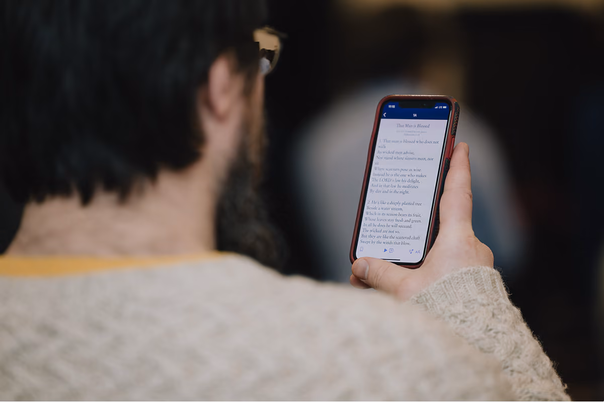 Close-up of a worshipper holding a phone showing a psalm during singing