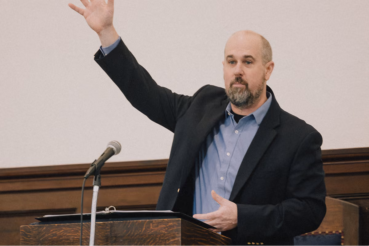 Pastor preaching from the pulpit with a raised hand during the Sunday service