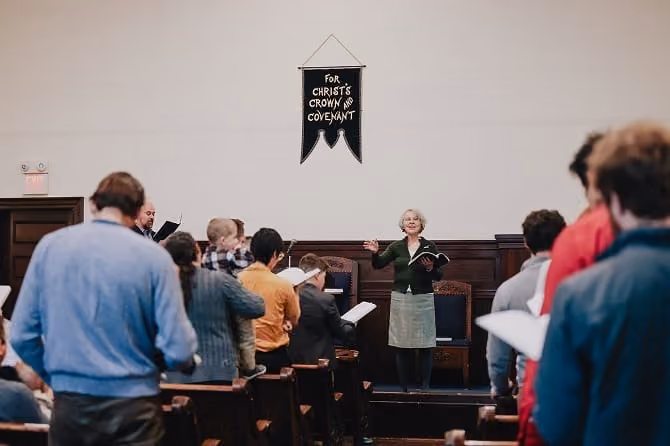 Congregation singing, led from the front beneath the church banner