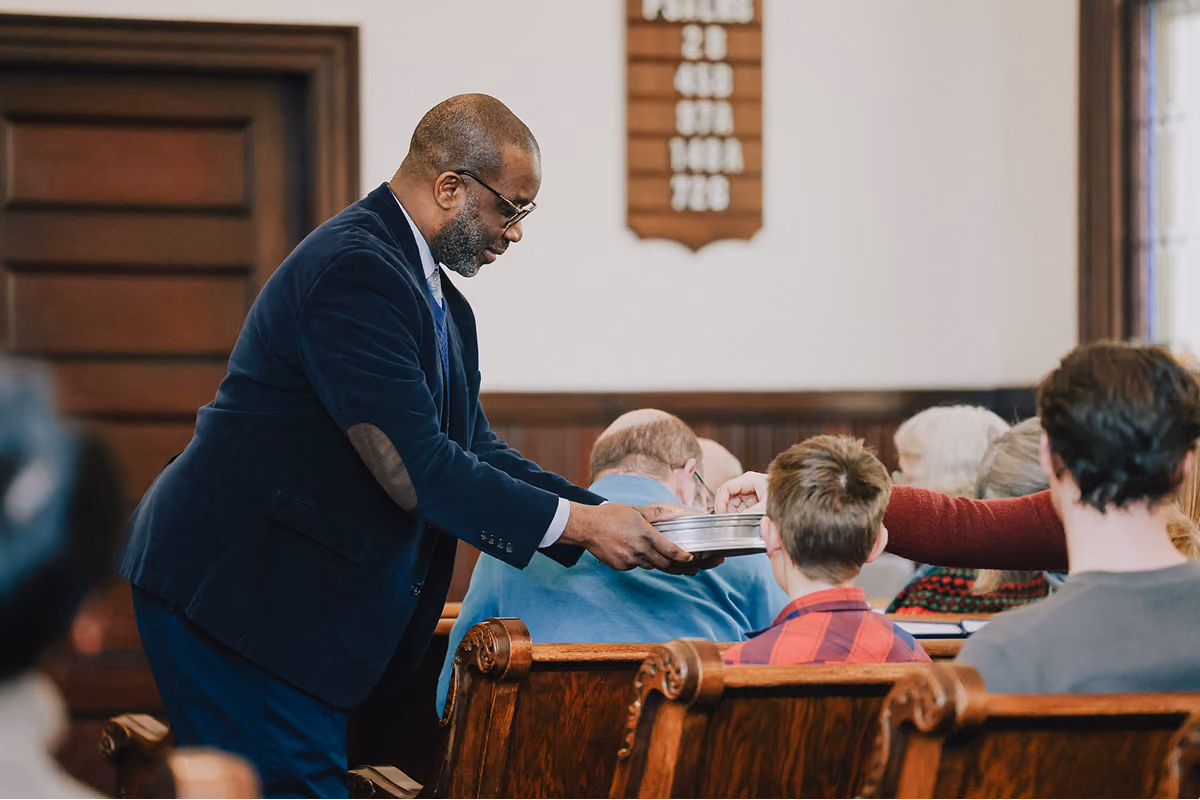 A elder passing communion to seated congregants