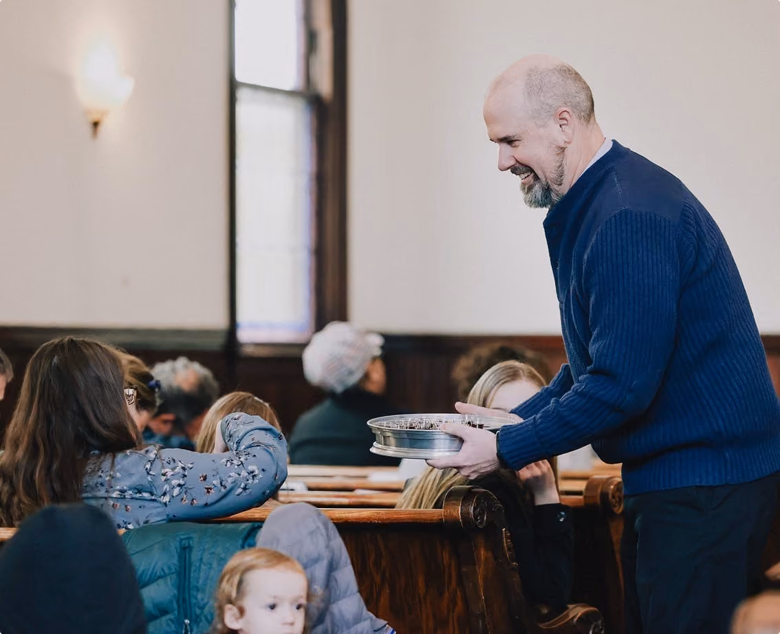 A man serving the seated congregation during the Sunday service