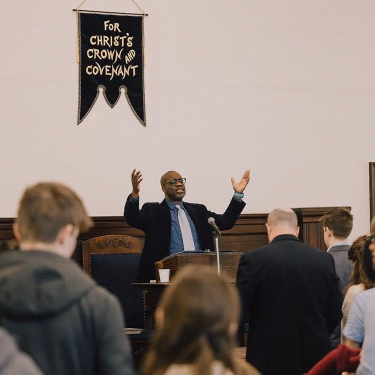 Worship service with the pastor preaching beneath the church banner